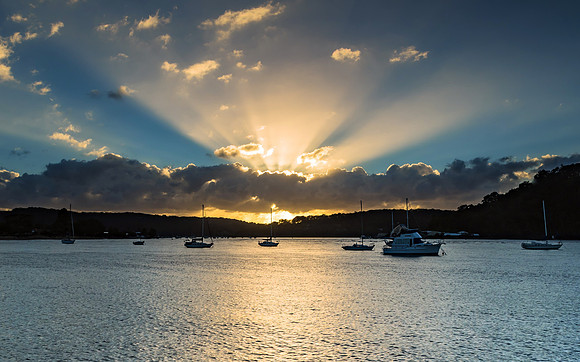 Sunrise Waterscape with Boats and Sun Rays