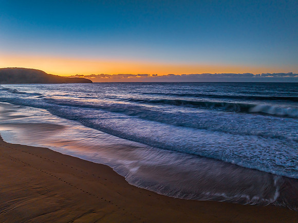 Sunrise seascape with waves and a low cloud bank