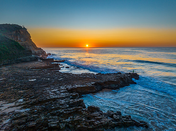 Sunrise over the ocean and rock platform with clear skies