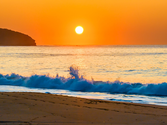 Soft sunrise seascape with full sun in a hazy cloudless sky