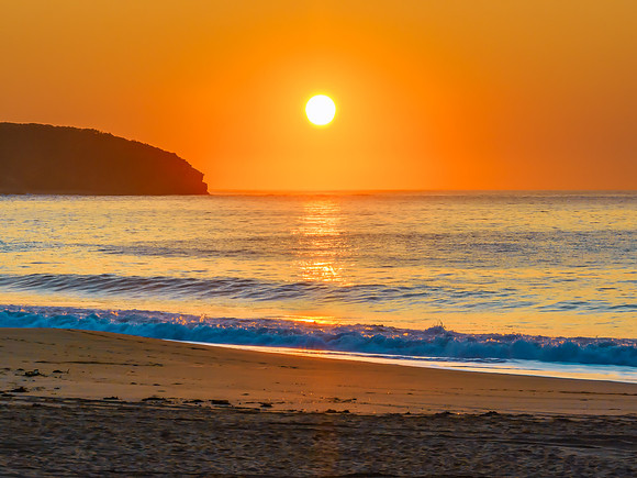Soft sunrise seascape with full sun in a hazy cloudless sky