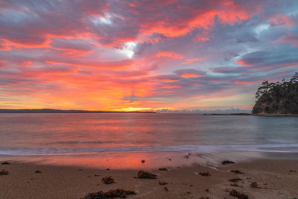 Cloud covered sunrise seascape tinged with pink