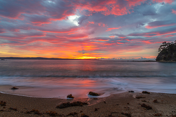 Cloud covered sunrise seascape tinged with pink