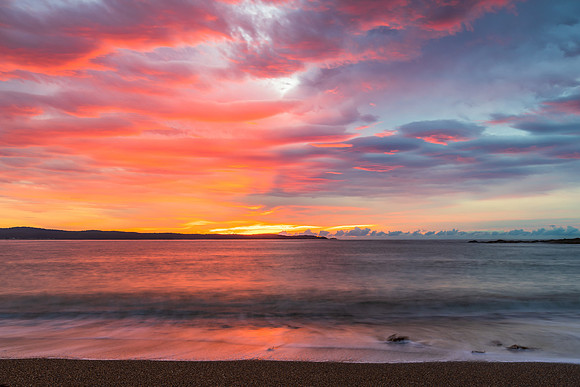 Cloud covered sunrise seascape tinged with pink