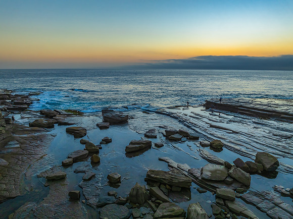 Sunrise seascape and rocky Inlet with thick fog cloud over the o