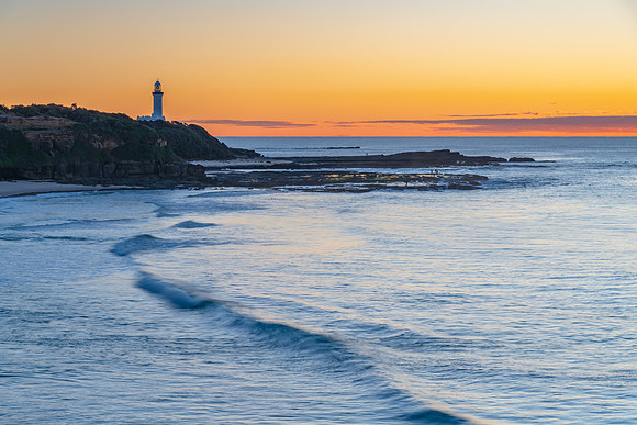 Sunrise seascape with lighthouse in the distance