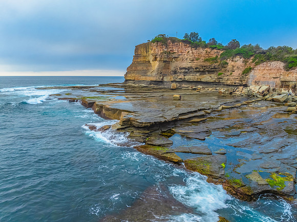 Sunrise seascape and rocky Inlet with thick fog cloud over the o