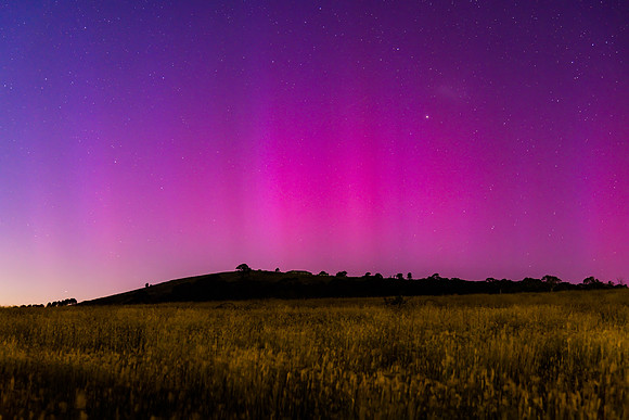 Aurora Australis display lights up the predawn sky in pinks