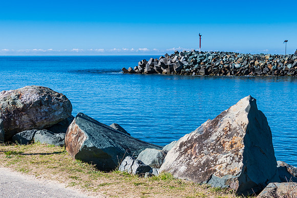 The blue river leading into the sea and rocky breakwall