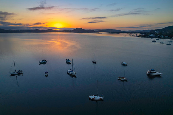 Sunrise waterscape with boats, soft clouds and reflections