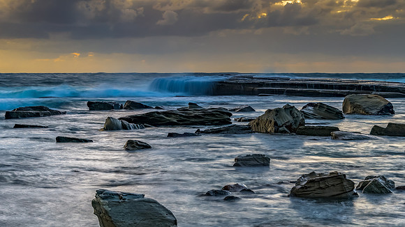 Moody sunrise seascape with clouds at the rocky inlet