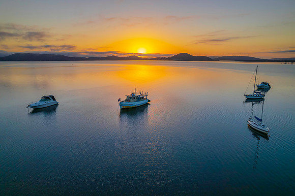 Sunrise waterscape with boats, soft clouds and reflections
