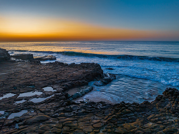 Sunrise over the ocean and rock platform with clear skies
