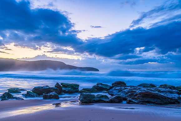 Sunrise seascape with low clouds and waves