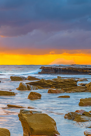 Moody sunrise seascape with clouds at the rocky inlet