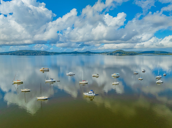 Aerial views over the bay with clouds, reflections and boats