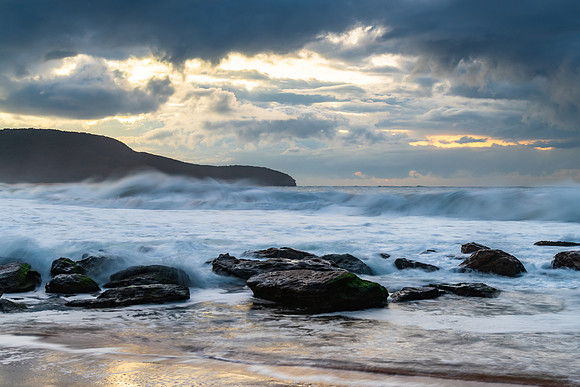 Sunrise seascape with low clouds and waves