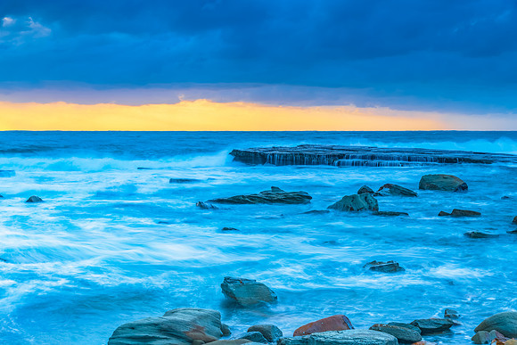 Moody sunrise seascape with clouds and cascades at the rocky inl