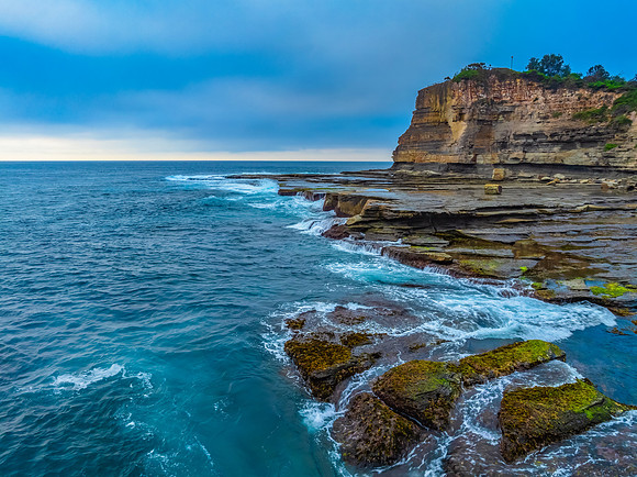 Sunrise seascape and rocky Inlet with thick fog cloud over the o