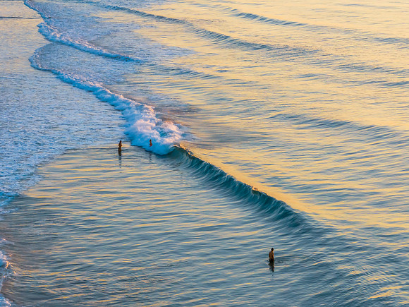 Top down view sunrise seascape with swimmers on a warm Spring da