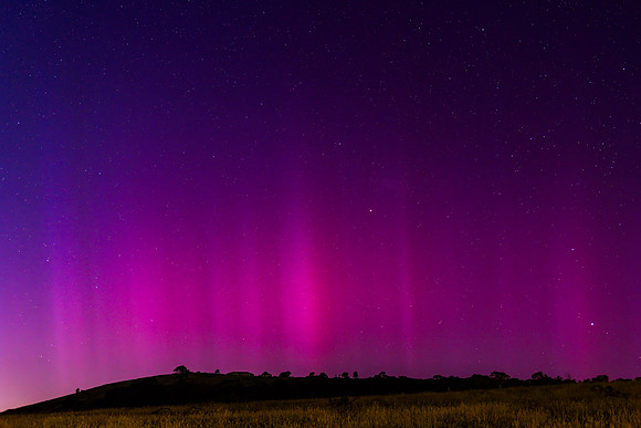 Aurora Australis display lights up the predawn sky in pinks