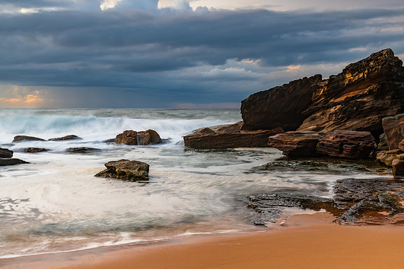 Sunrise seascape with low clouds and waves