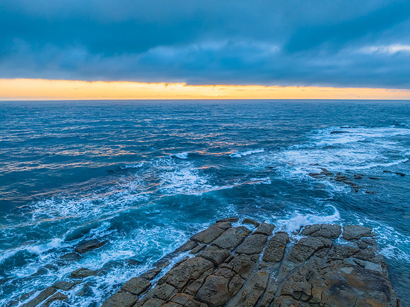 Cloudy sunrise over the ocean with rock platform
