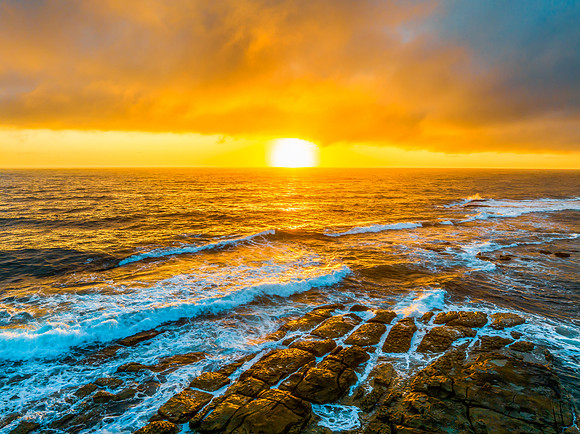 Cloudy sunrise over the ocean with rock platform