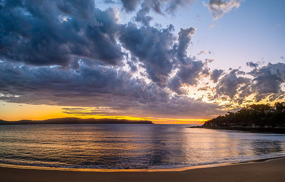Sunrise over the ocean with clouds and a calm sea