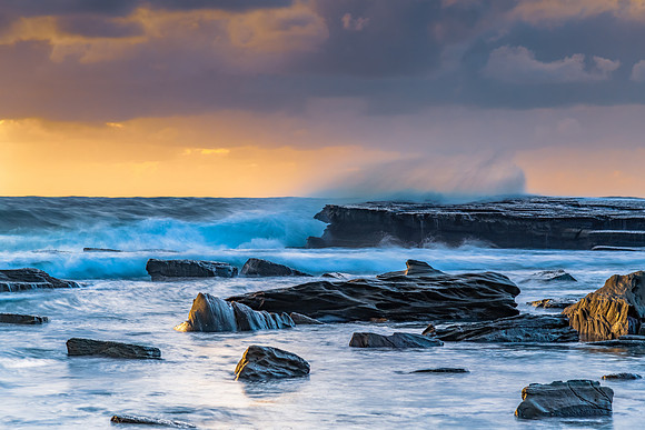 Moody sunrise seascape with clouds at the rocky inlet
