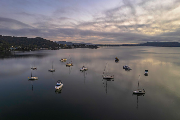 Sunrise waterscape with boats, soft clouds and reflections