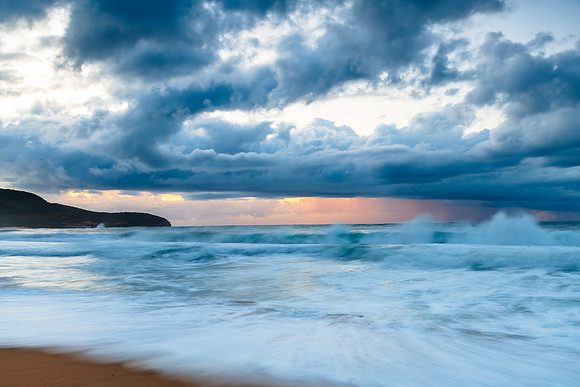 Sunrise seascape with low clouds and waves