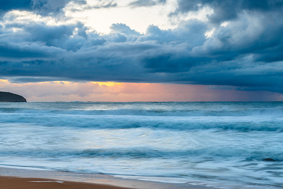 Sunrise seascape with low clouds and waves