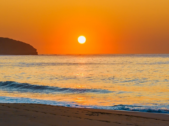 Soft sunrise seascape with full sun in a hazy cloudless sky
