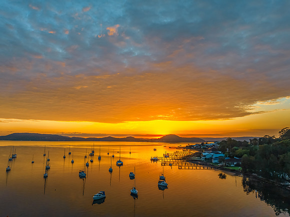 Aerial sunrise over the water with boats and clouds