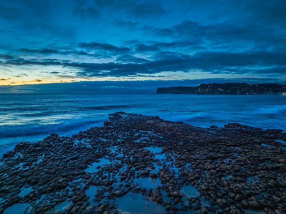 Sunrise over the sea and rock platform with high cloud