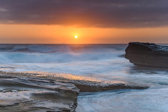 An Atmospheric Sunrise Seascape with Large Rocks