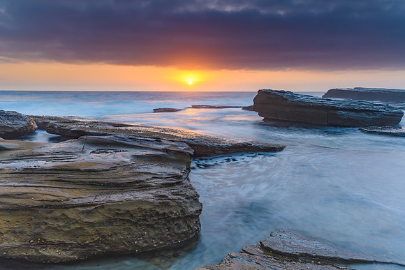 An Atmospheric Sunrise Seascape with Large Rocks