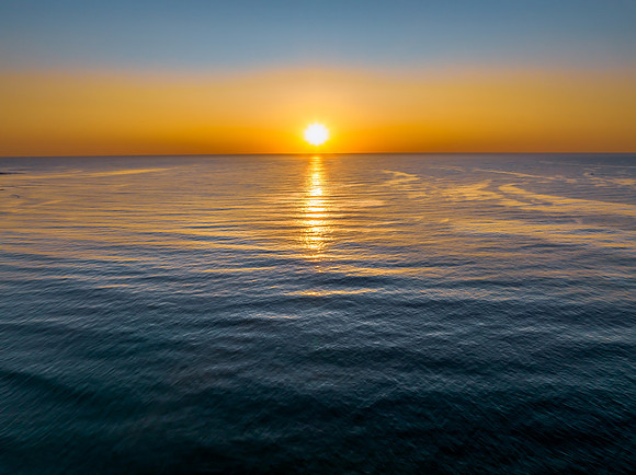Aerial sunrise seascape with a hazy sky from fire reduction burn