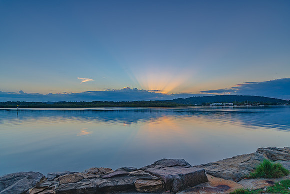 Sunrise waterscape with cloud reflections and sun rays