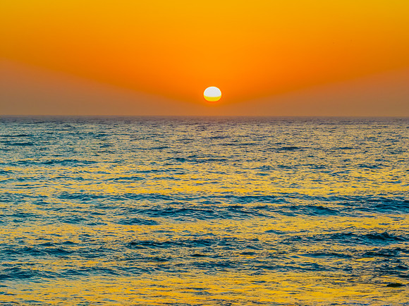 Sunrise over the blue ocean with orange hazy sky and the sun ris