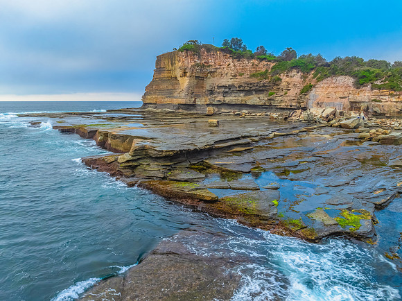 Sunrise seascape and rocky Inlet with thick fog cloud over the o