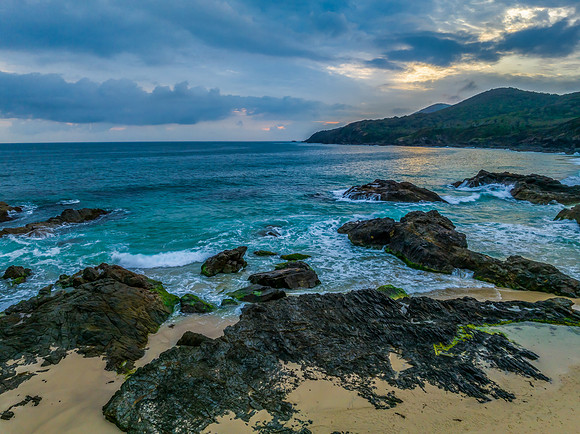 Rain clouds, rocks and sunrise at the seaside