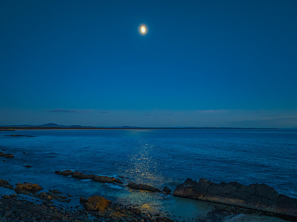 Seascape under the moonlight in the blue hour of dawn with Rock