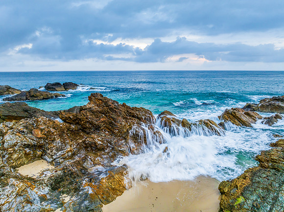 Rain clouds, rocks and sunrise at the seaside