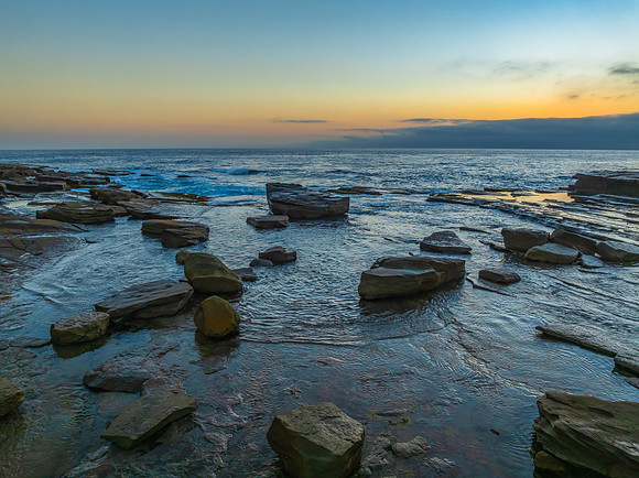 Sunrise seascape and rocky Inlet with thick fog cloud over the o
