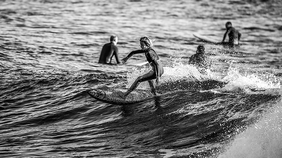 Young surfer catching a wave in black and white