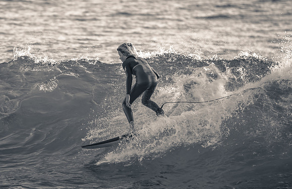 Early morning seascape with surfer catching a wave