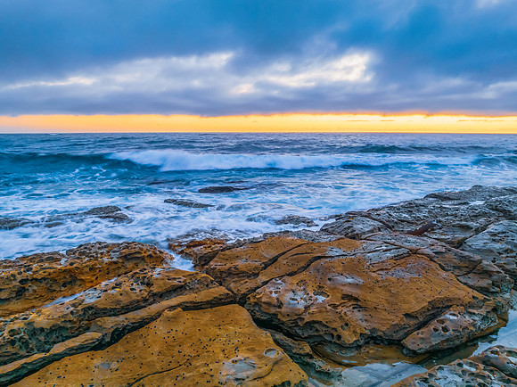 Cloudy sunrise over the ocean with rock platform
