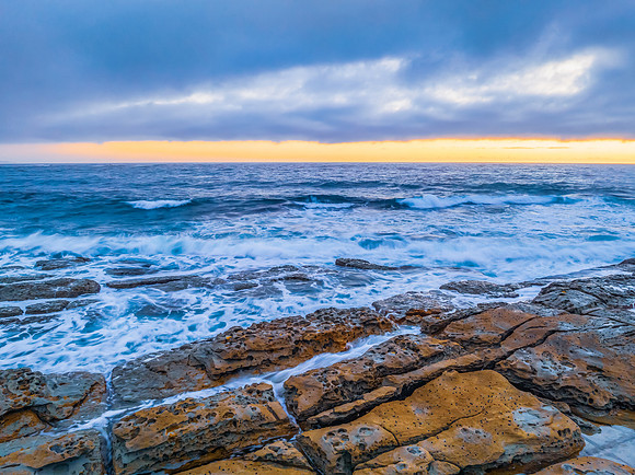 Cloudy sunrise over the ocean with rock platform